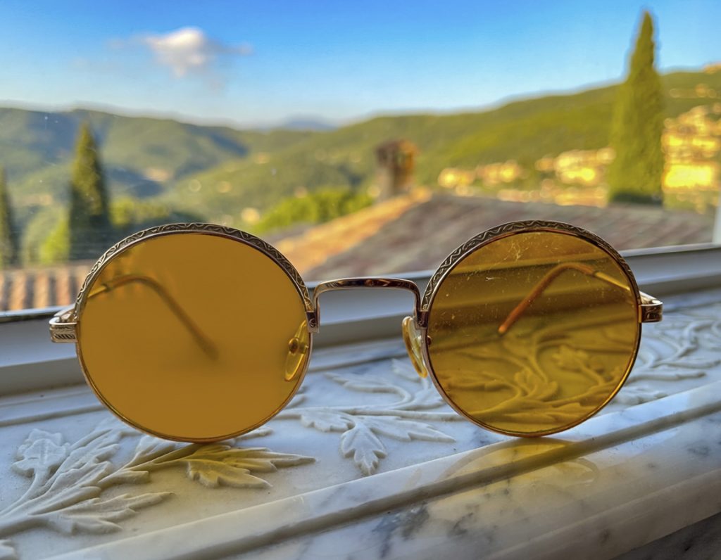 A pair of tinted spectacles set down on a table, the world beyond them in true colour.